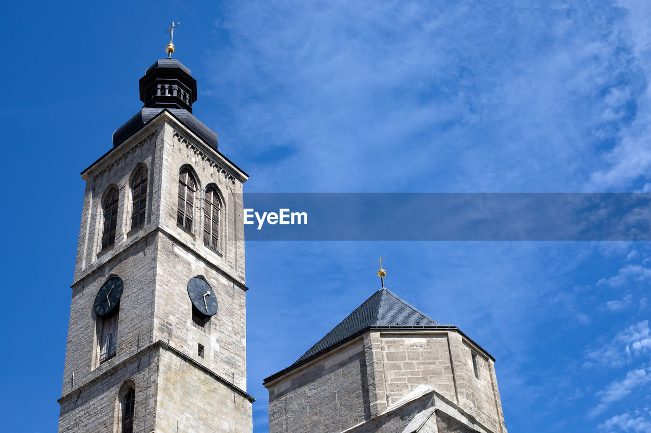 A clock tower of the catholic church against the blue sky on sunny day with copy space