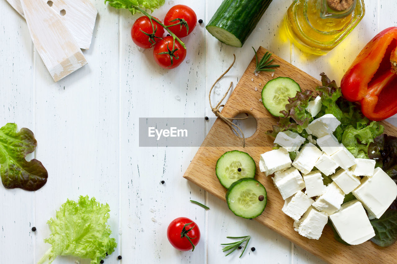 Cooking qreek salad with fresh vegetables, feta cheese and black olives. 