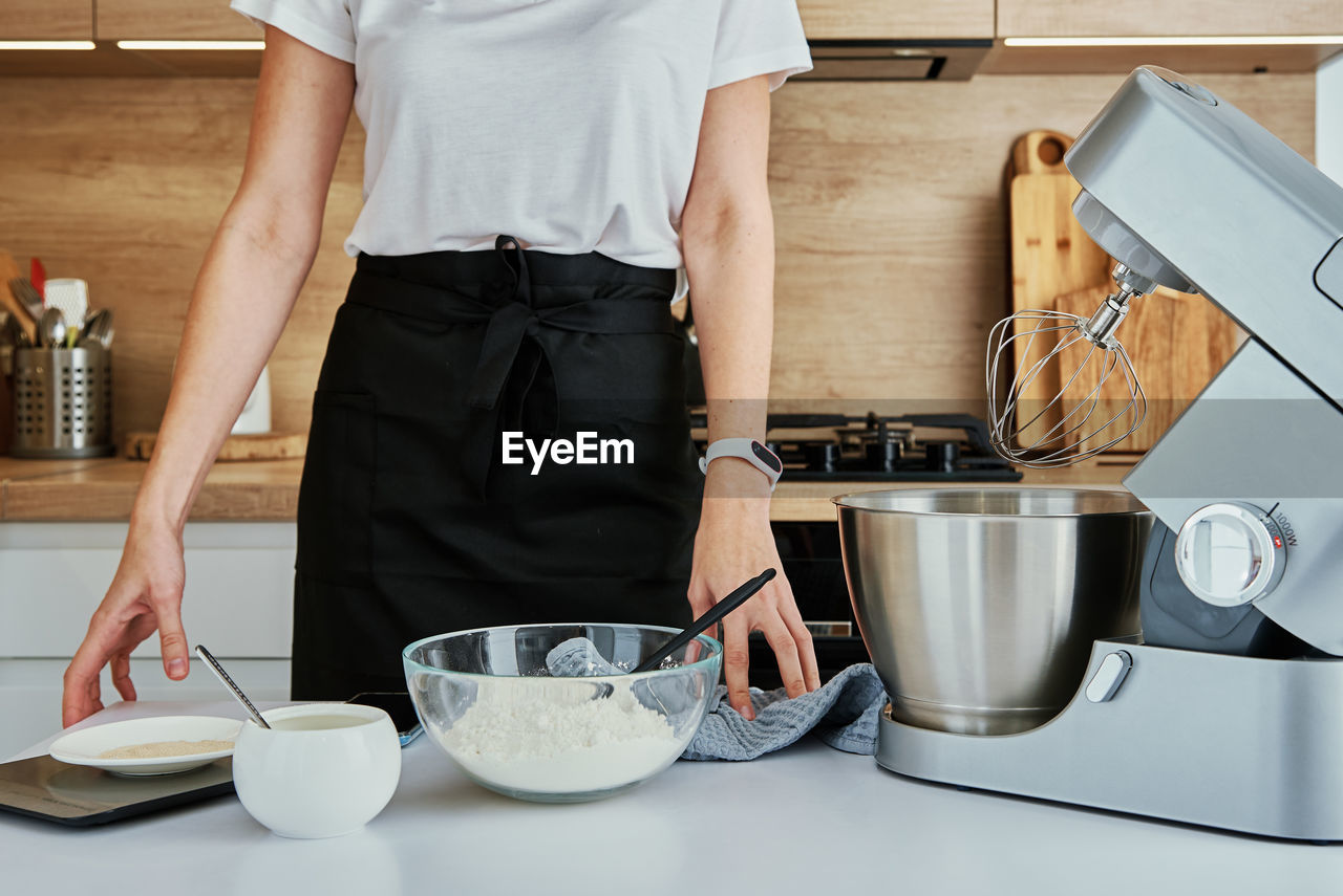 Woman cooking at kitchen and using kitchen machine