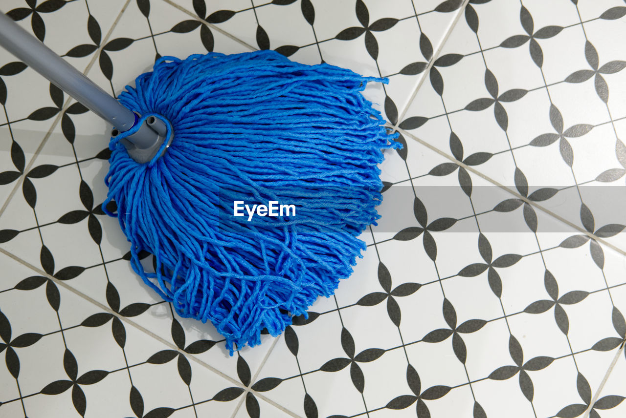 Blue mop brush on black and white bathroom floor