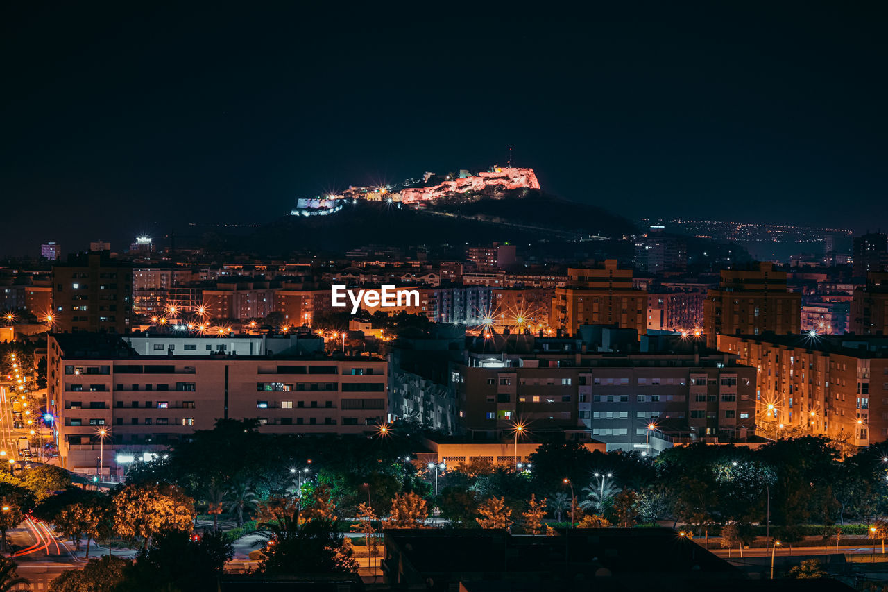 Illuminated buildings in city against sky at night