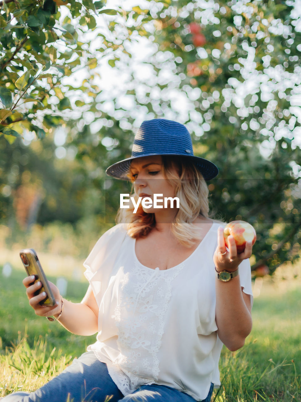 FULL LENGTH OF WOMAN USING MOBILE PHONE WHILE STANDING ON FIELD