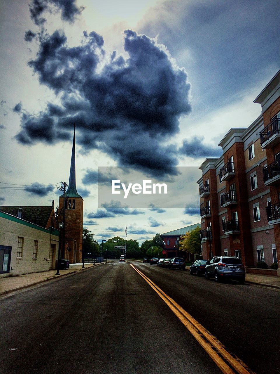 VIEW OF CITY STREET AGAINST CLOUDY SKY