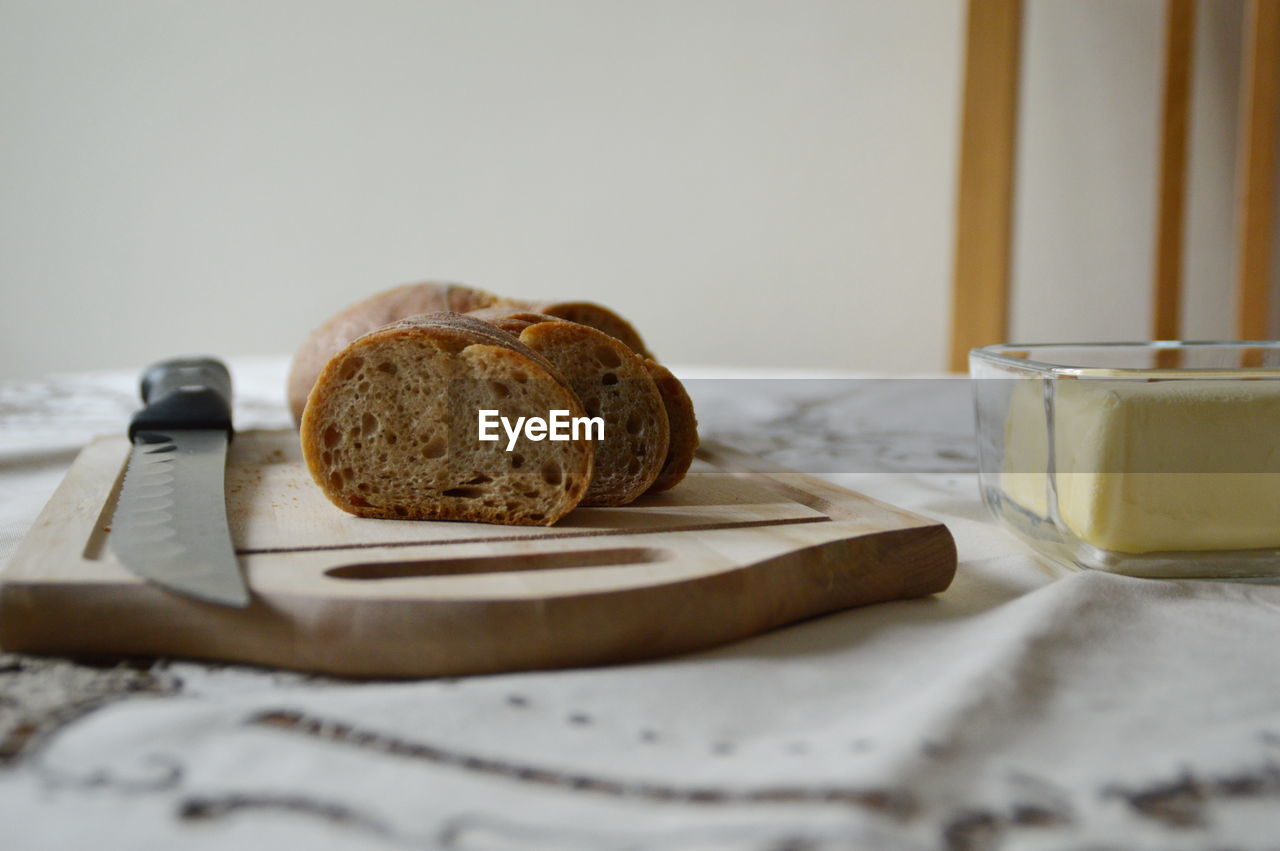 Close-up of bread slices on cutting board by butter at table