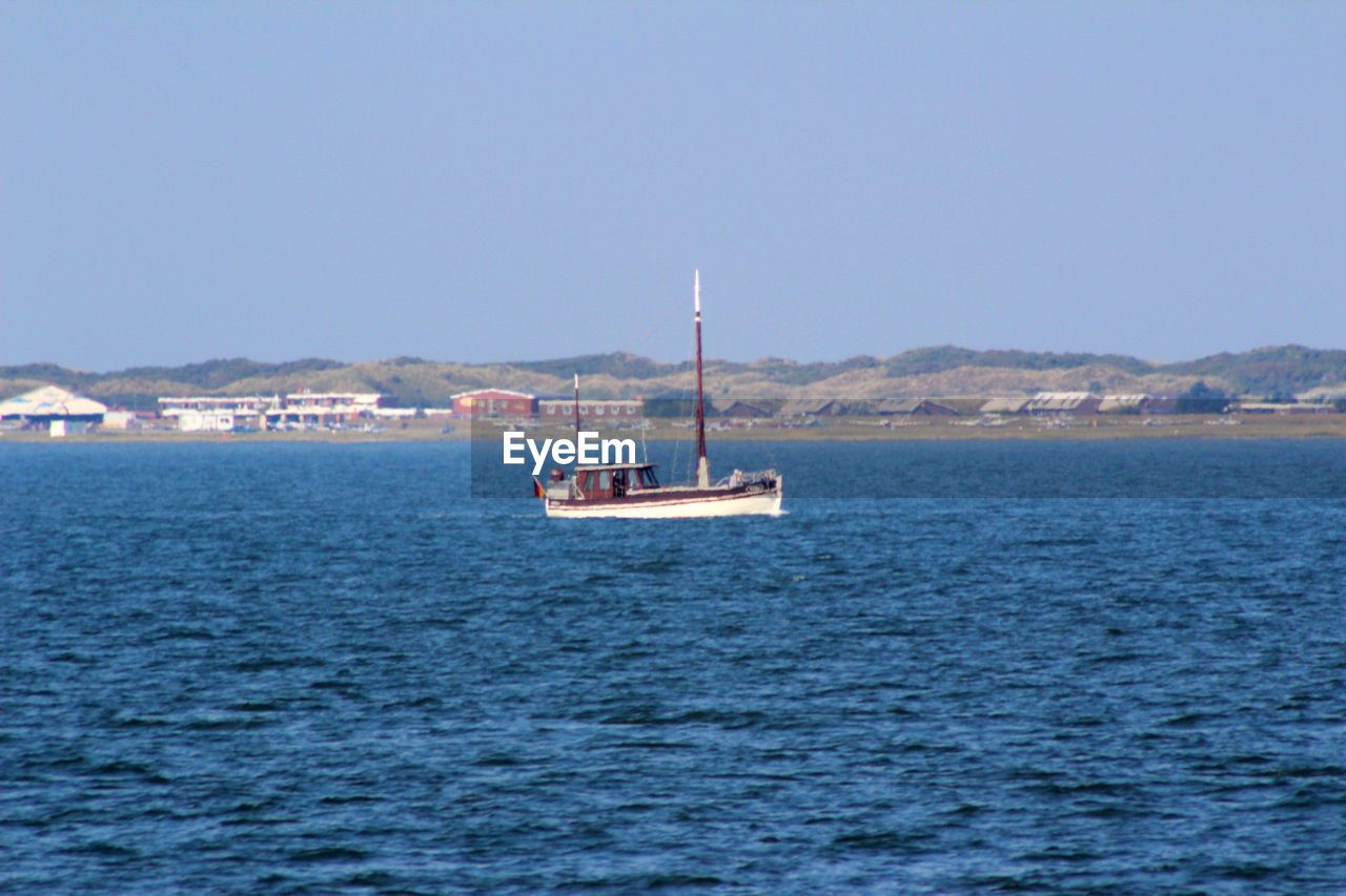 BOAT SAILING IN SEA AGAINST CLEAR SKY