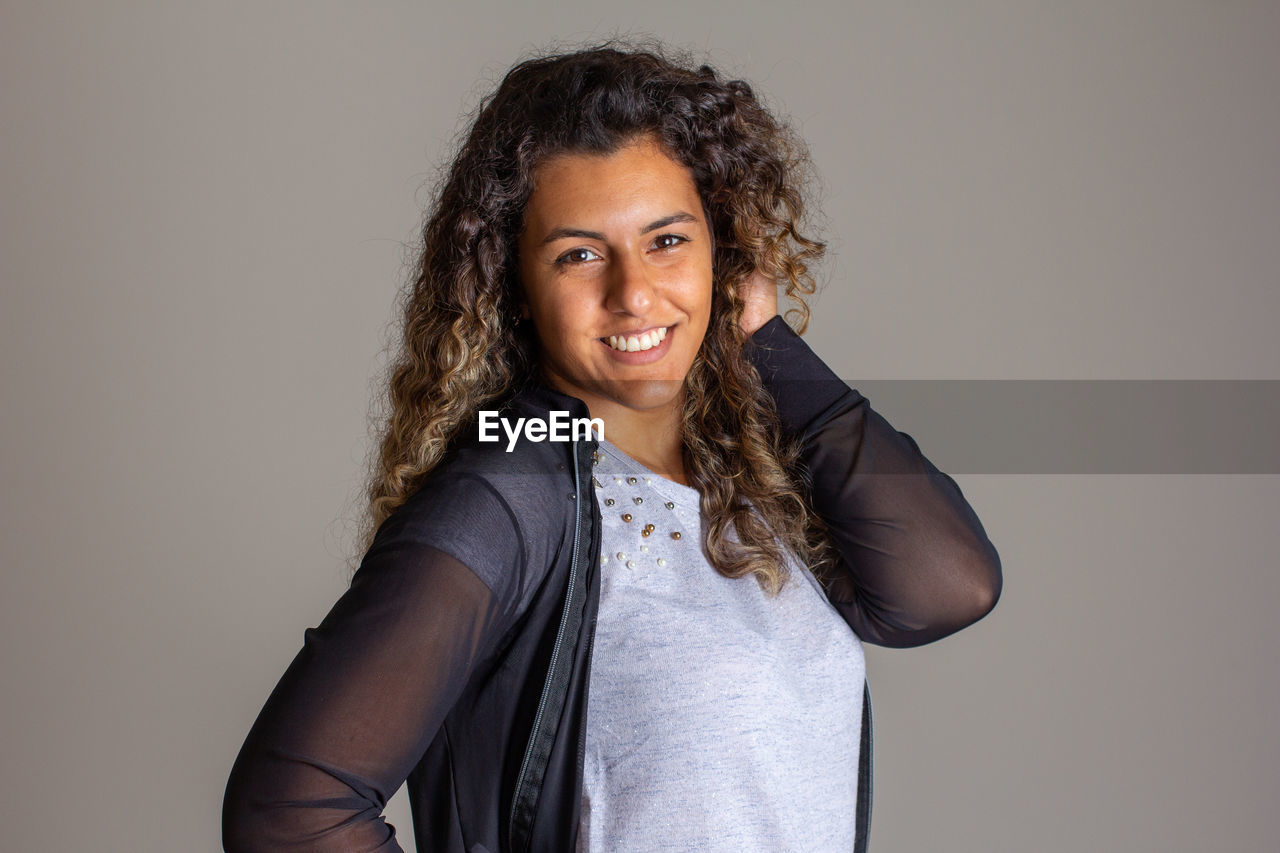 PORTRAIT OF A SMILING YOUNG WOMAN OVER WHITE BACKGROUND