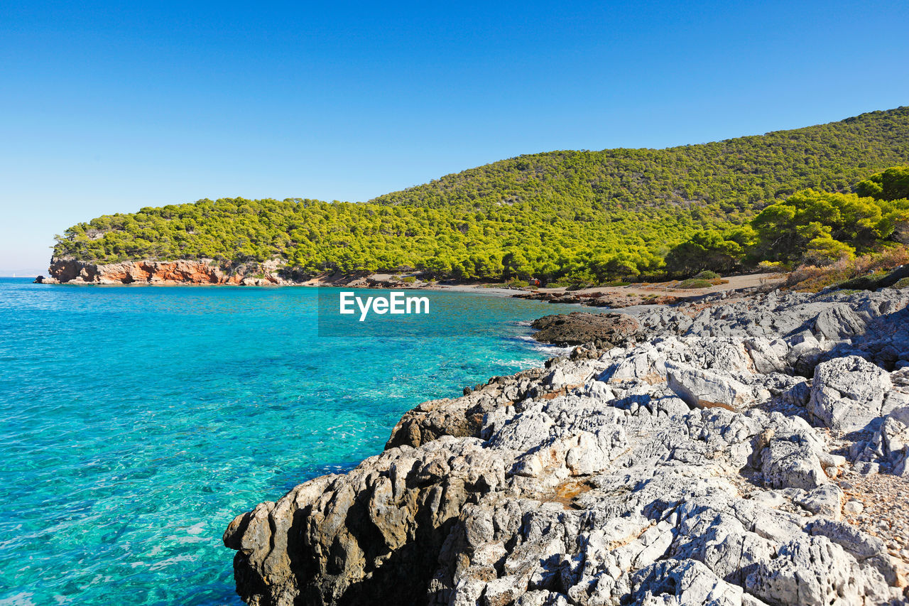 SCENIC VIEW OF ROCKS IN SEA AGAINST CLEAR BLUE SKY
