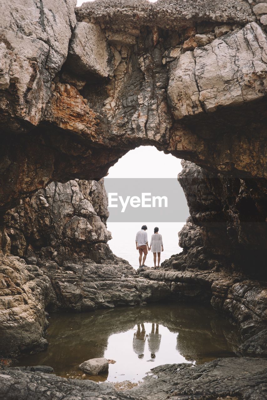 Rear view of couple standing at rock formation