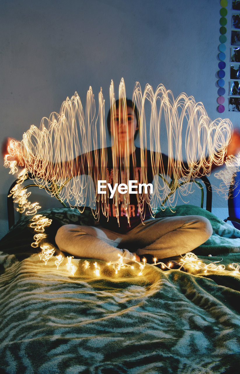 Woman with light painting sitting on bed