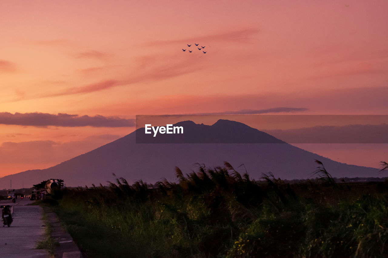 Scenic view of silhouette mountains against orange sky