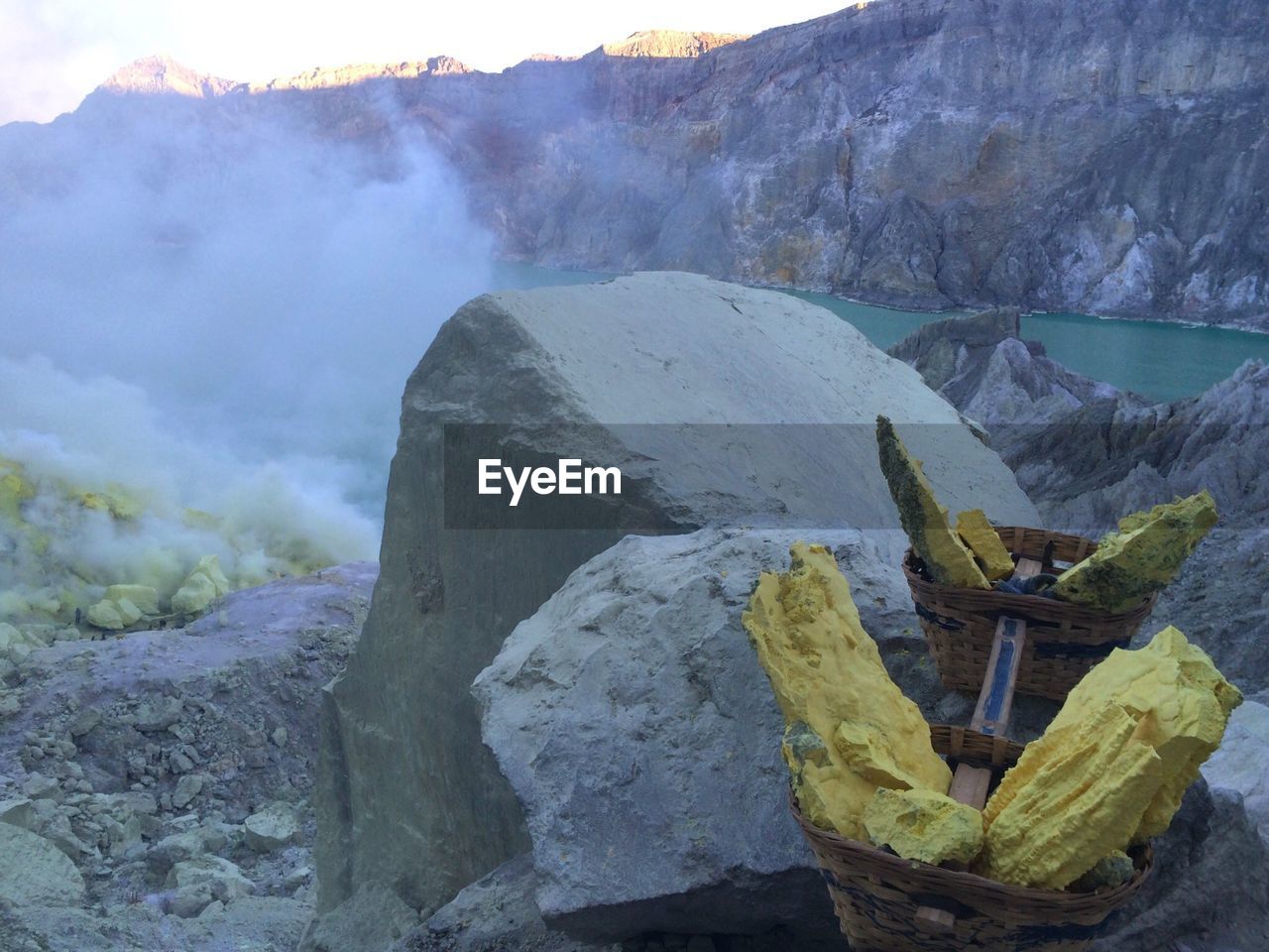 Sulphur rocks in basket on rocky mountain by blue lake