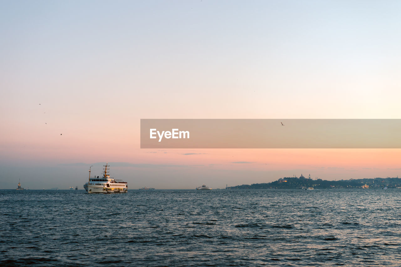 Boat sailing in sea against clear sky during sunset