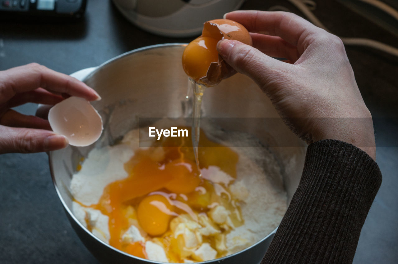 Cropped hand putting egg in flour and butter