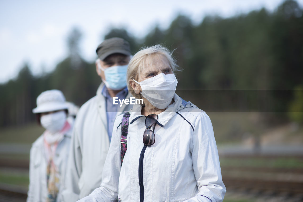 Group of elderly seniors people with face masks waiting train before traveling during a pandemic