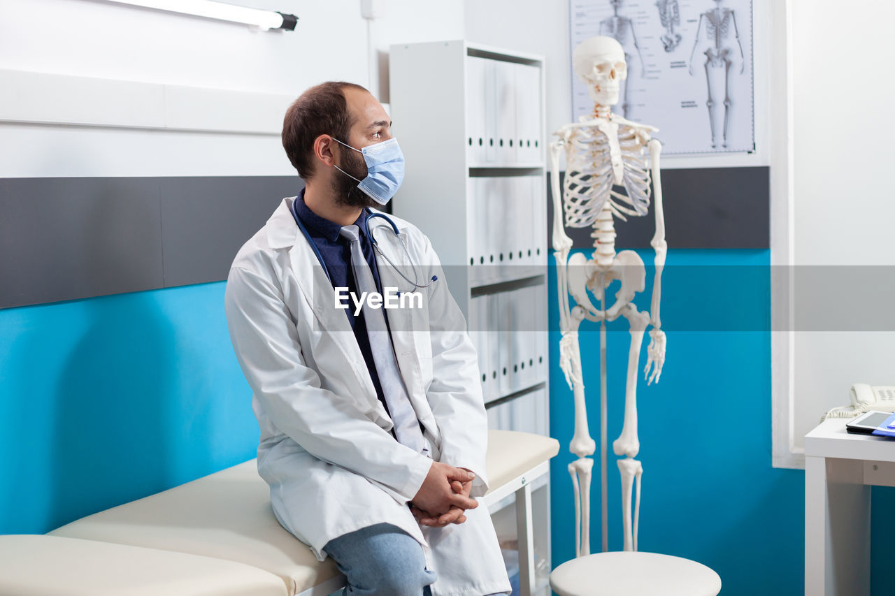 Doctor wearing mask sitting at hospital