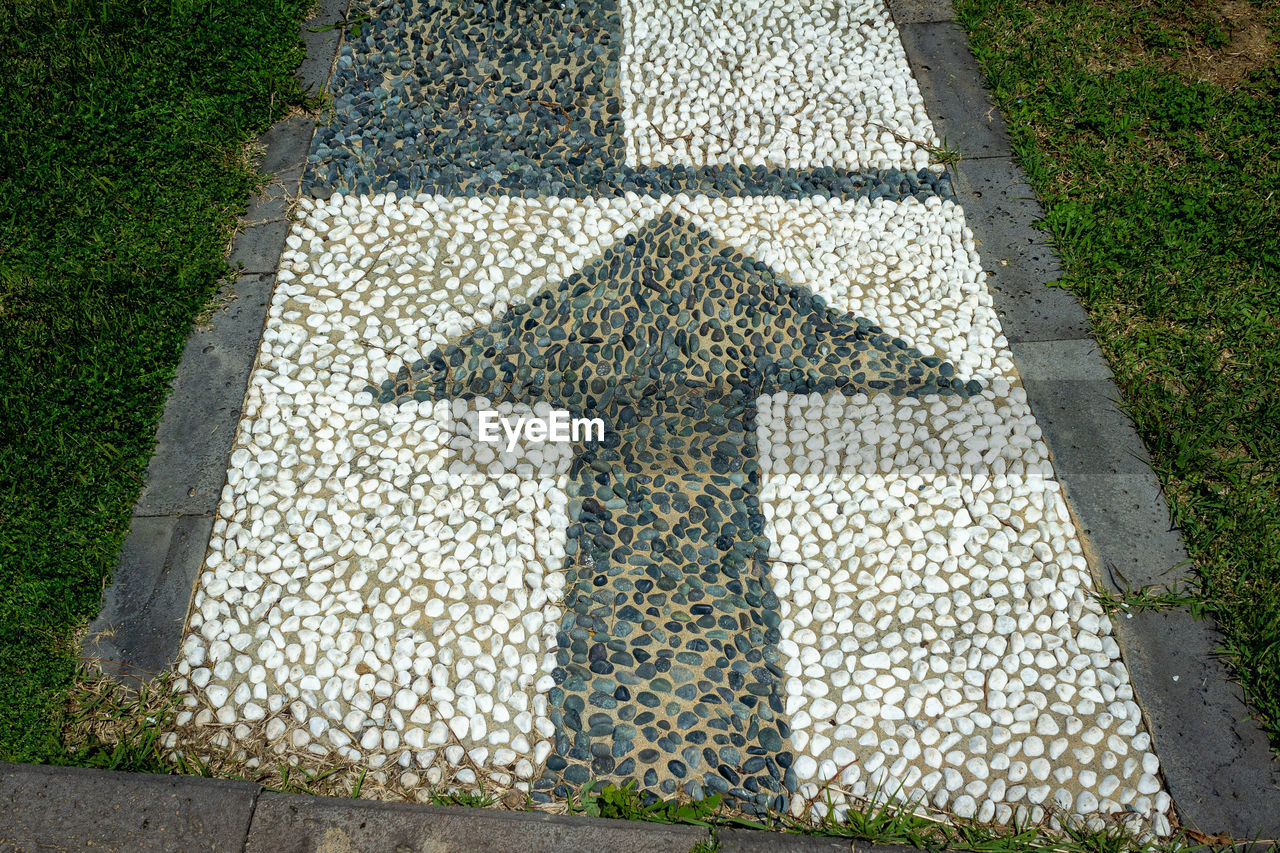 High angle view of arrow sign on footpath