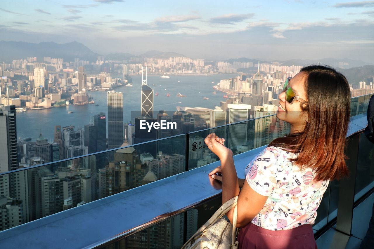 Woman in sunglasses standing against cityscape