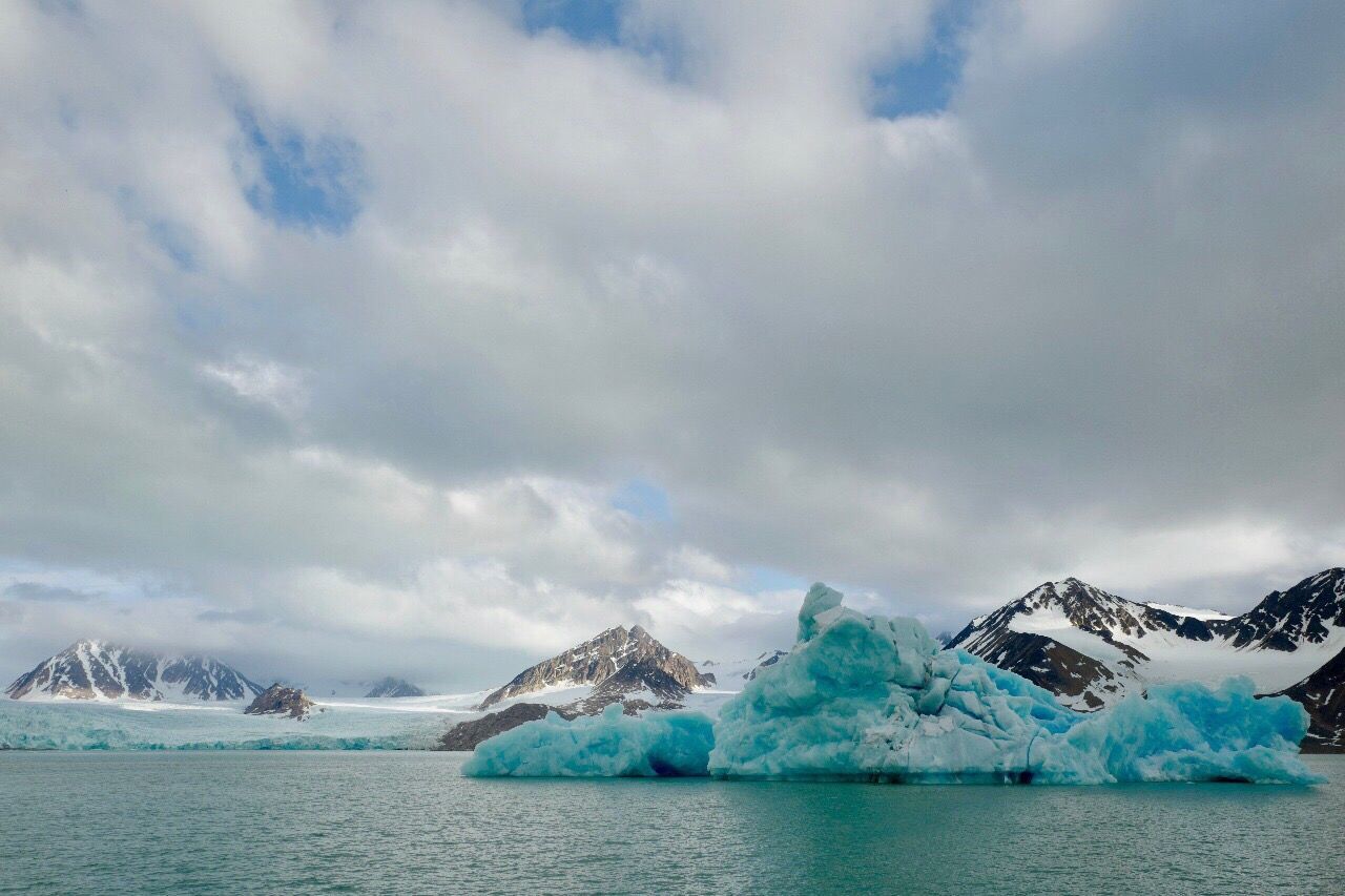 Scenic view of snow covered mountains by glacier in sea