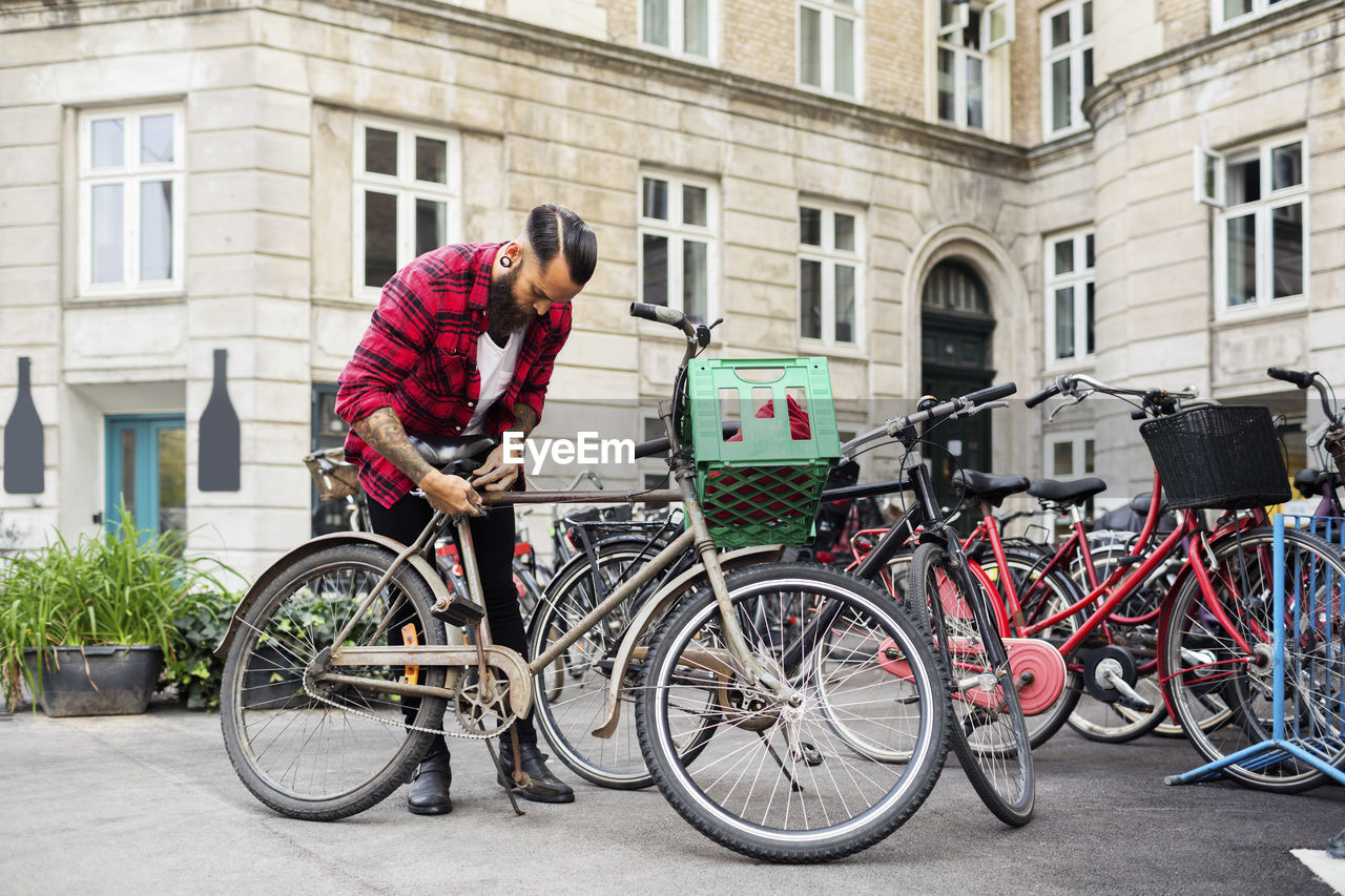 Owner locking bicycle at parking lot outside store