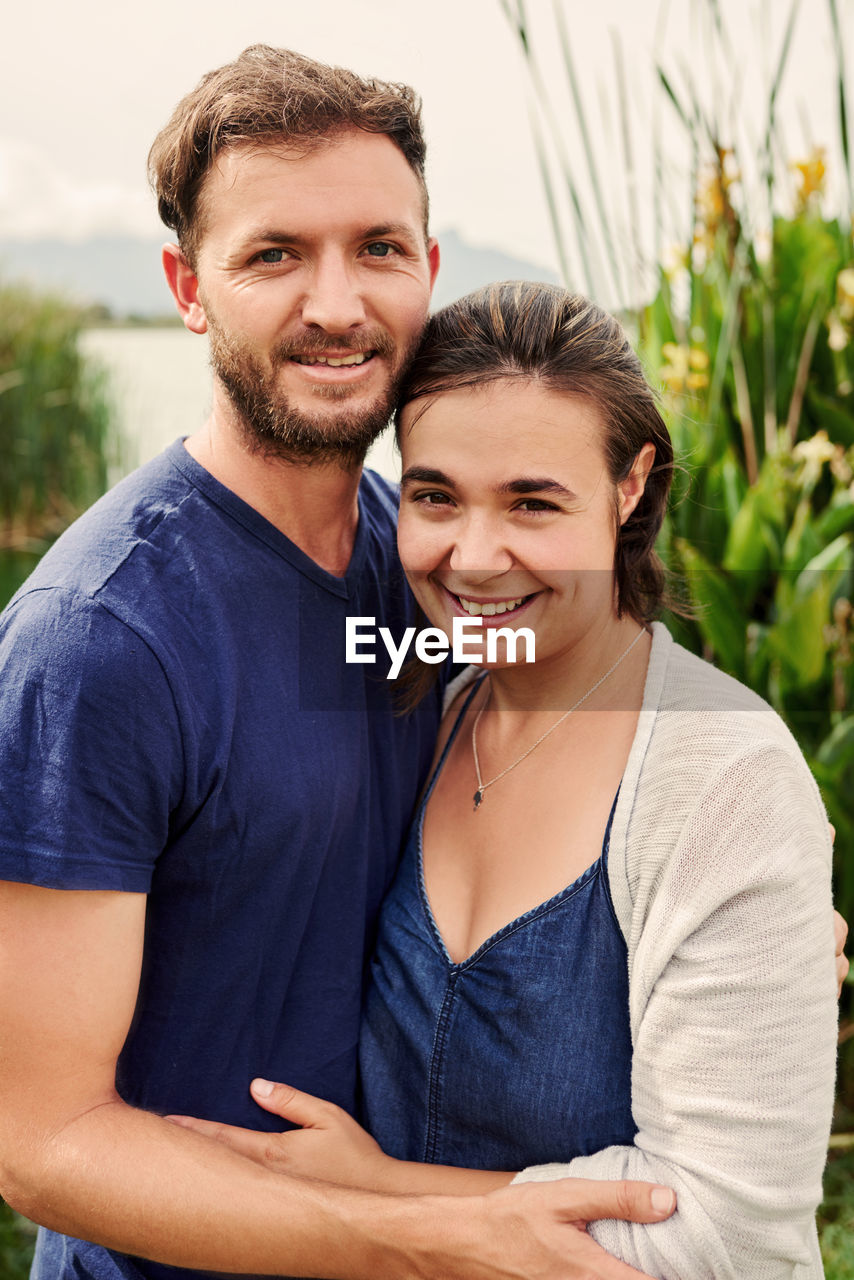 Portrait of smiling couple embracing by lake
