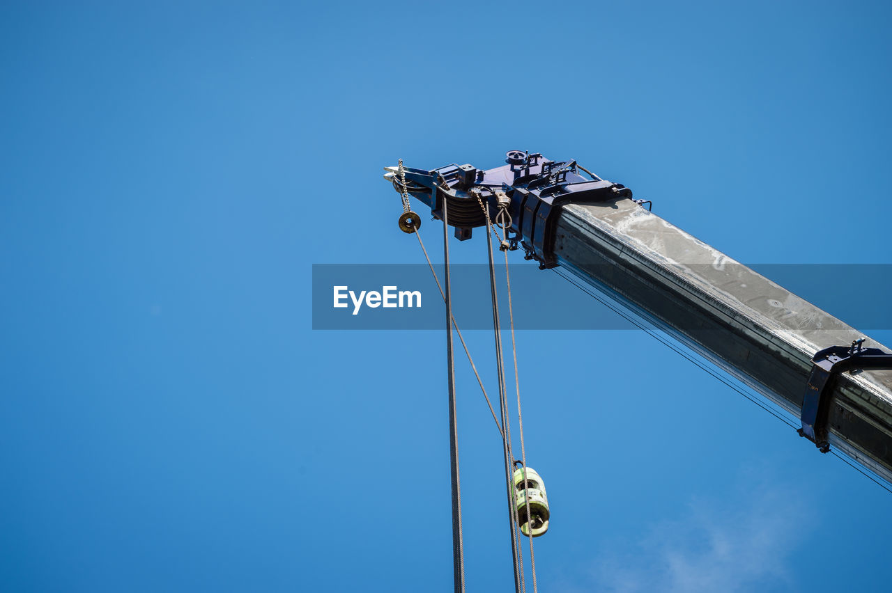 Low angle view of crane against clear blue sky