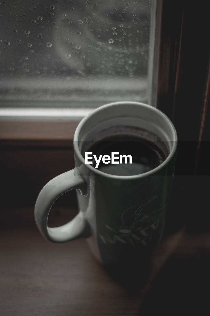 CLOSE-UP OF COFFEE CUP ON TABLE WITH WINDOW