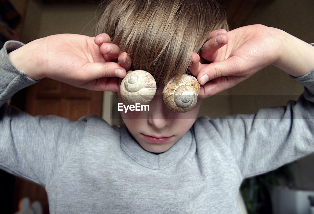 Close-up of boy holding snail shells at home