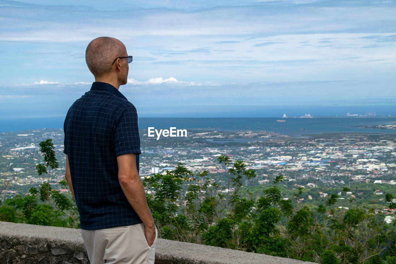 Man looking at city against sky