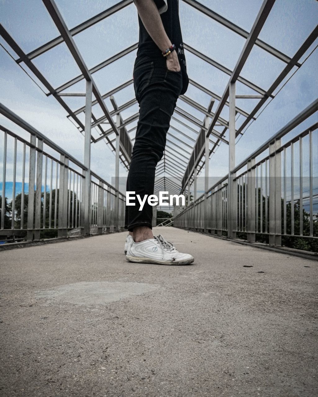 Low section of man standing on bridge