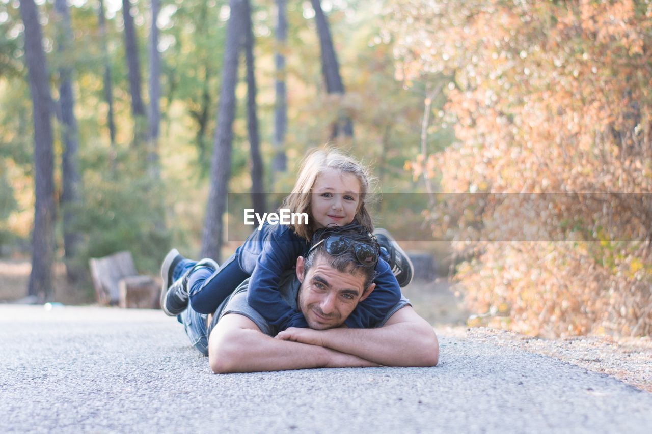 Portrait of father with daughter lying on road