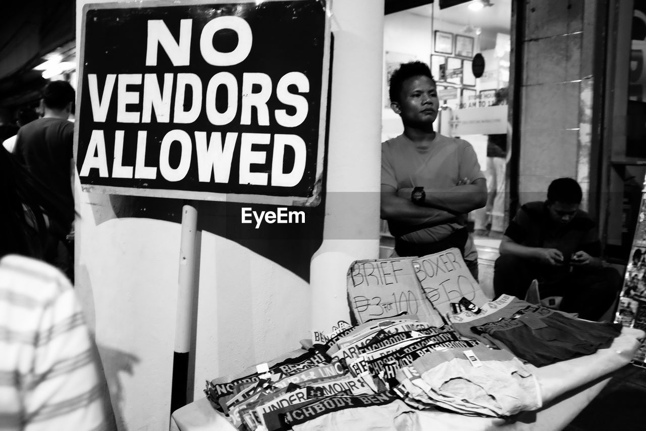 Vendor selling underwear by road sign in city at night