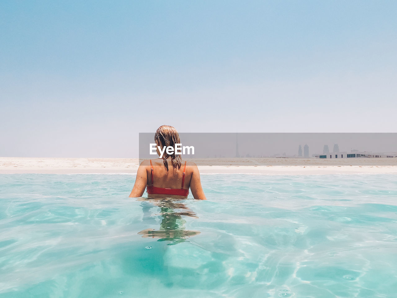 Rear view of woman swimming in sea against clear sky
