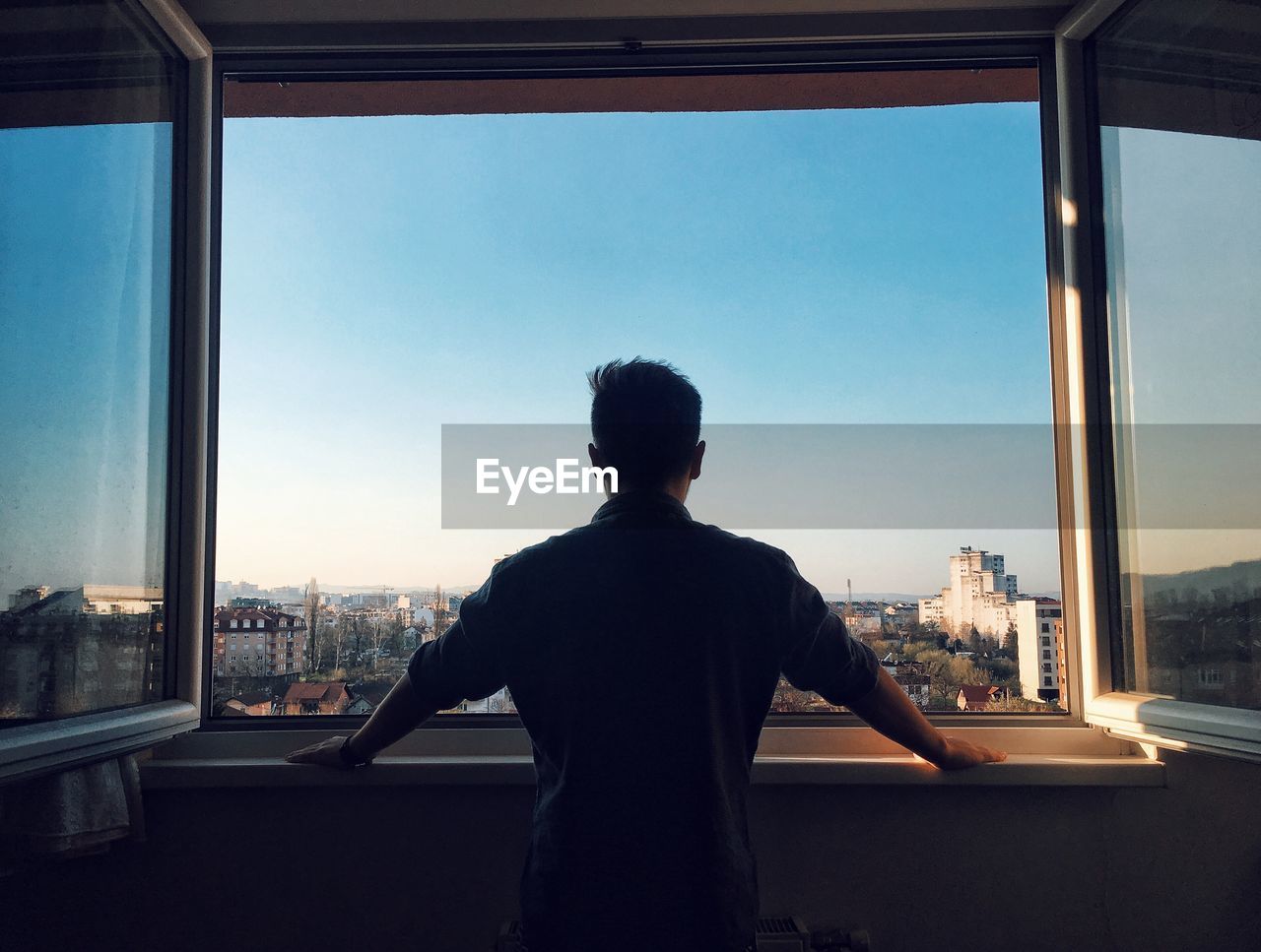 Rear view of man looking through window