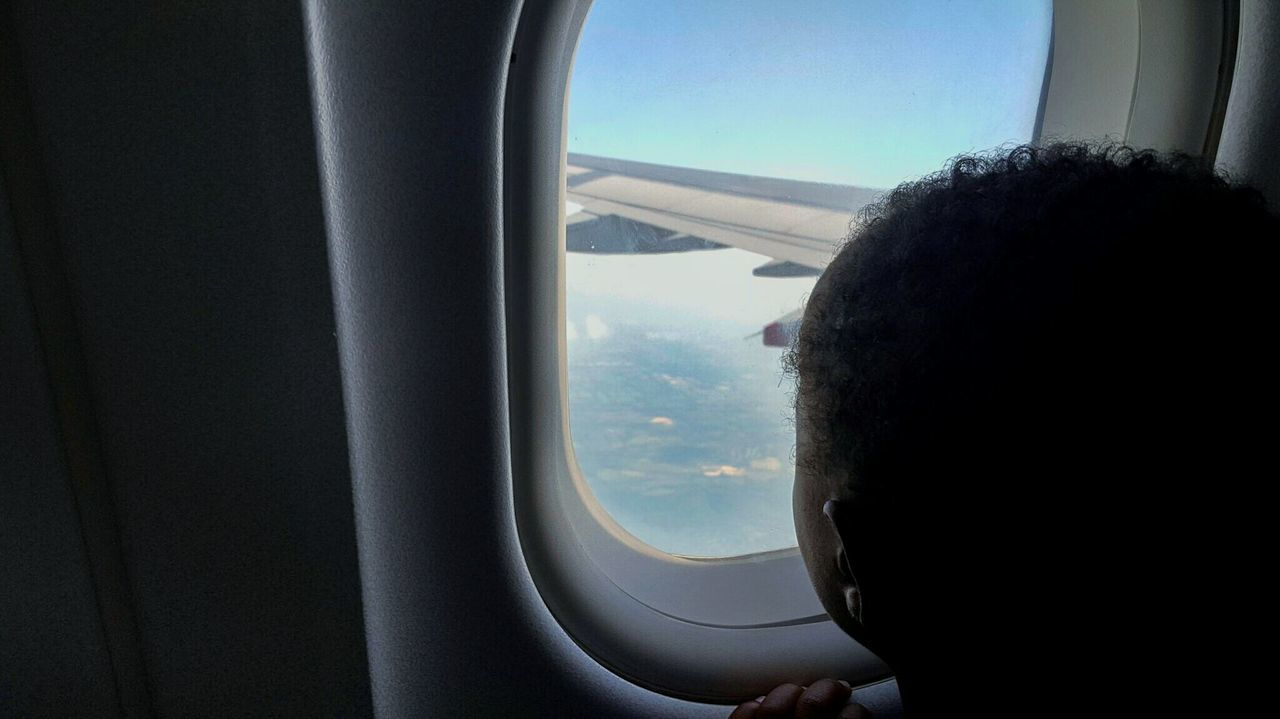 CLOSE-UP OF AIRPLANE WING SEEN THROUGH WINDOW OF BUS