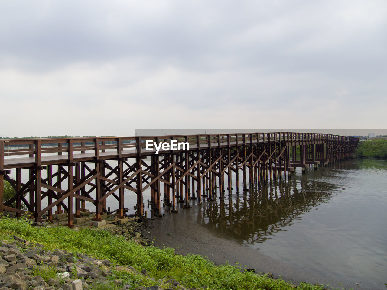 Bridge over calm sea against sky