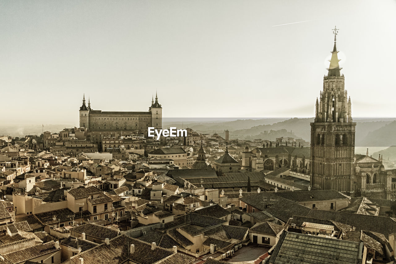 Bell tower of church amidst cityscape against clear sky