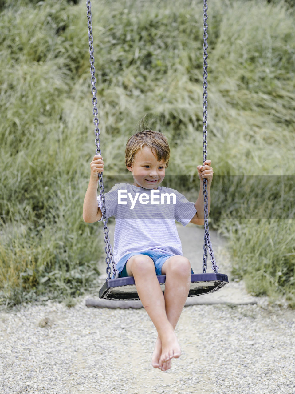 Full length of boy sitting on swing at playground