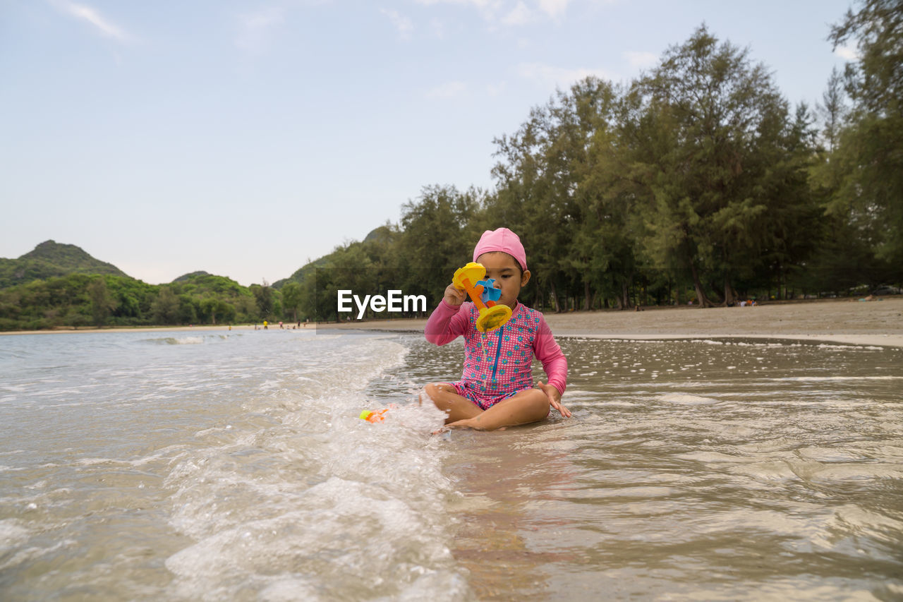 Girl playing with toy while sitting at beach