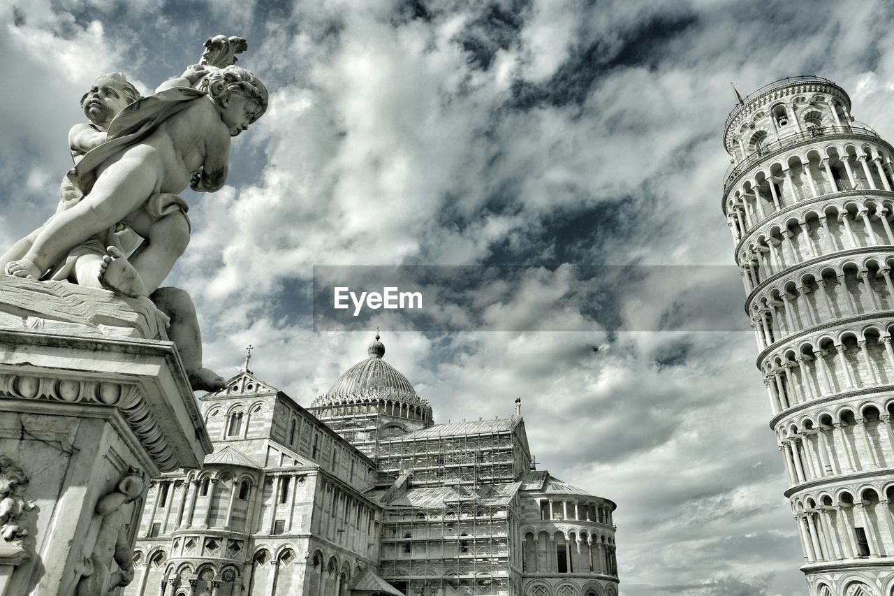 Low angle view of sculptures by historic buildings against sky