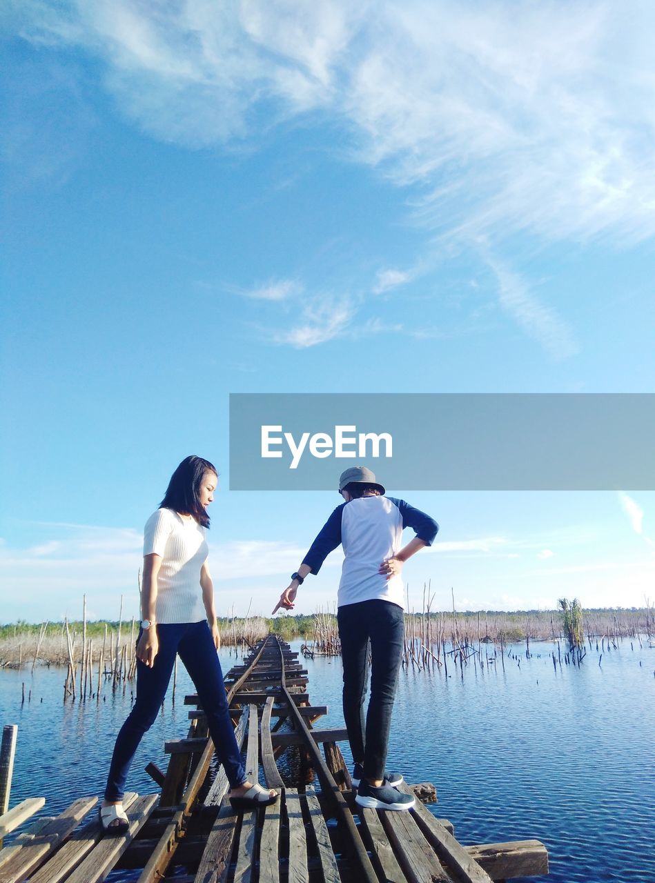 PEOPLE STANDING IN LAKE AGAINST SKY