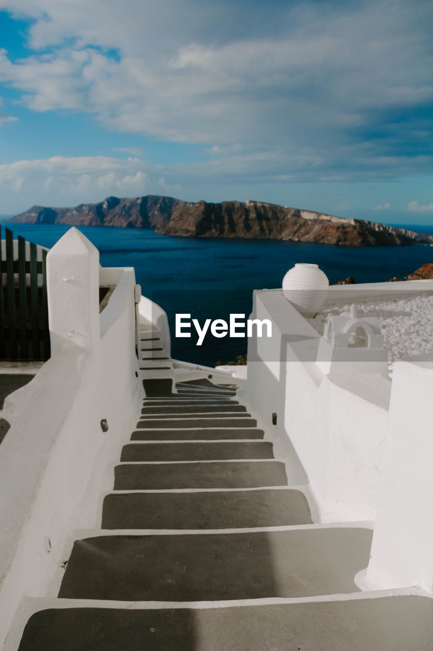 Staircase leading towards sea against sky