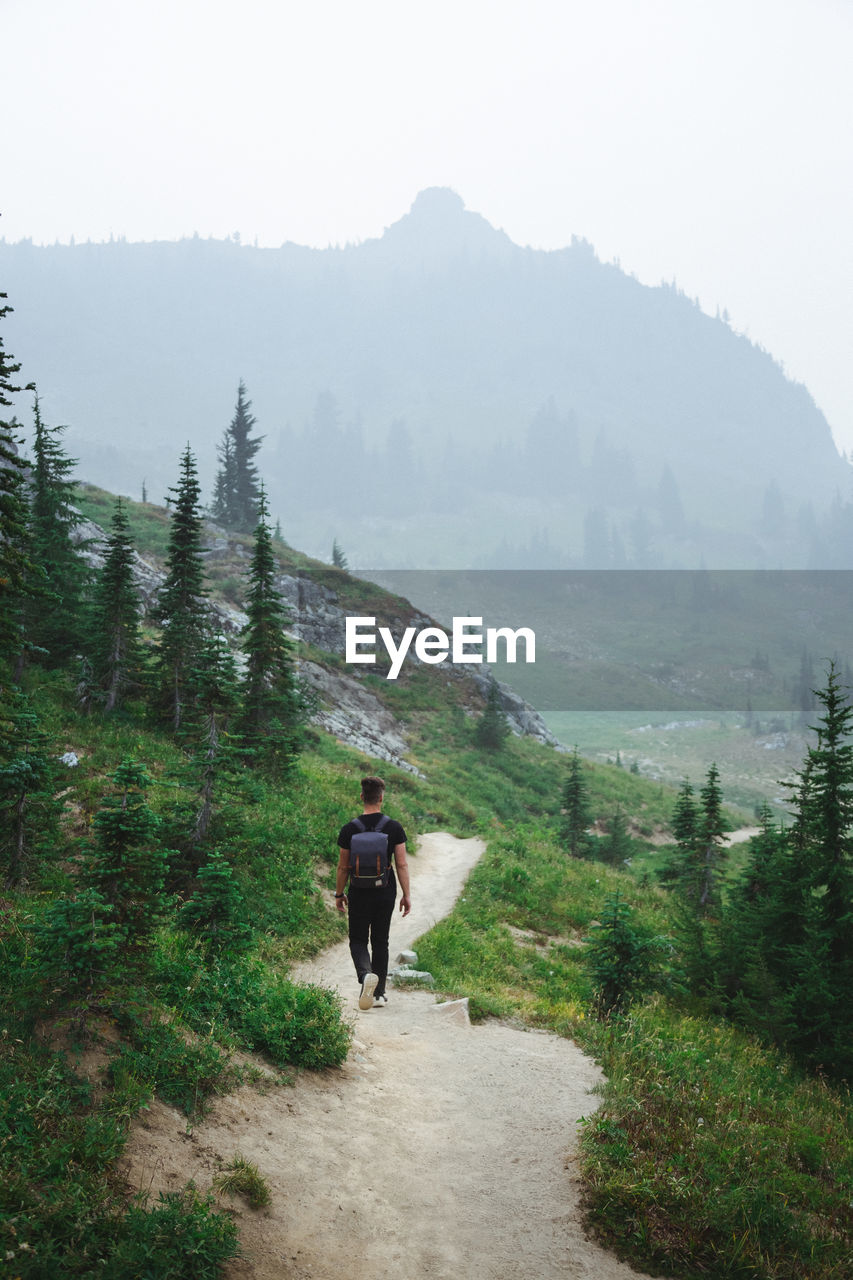 FULL LENGTH REAR VIEW OF MAN WALKING ON MOUNTAIN