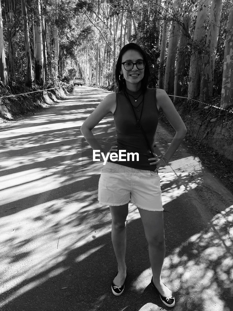 Portrait of smiling beautiful woman standing on street amidst trees