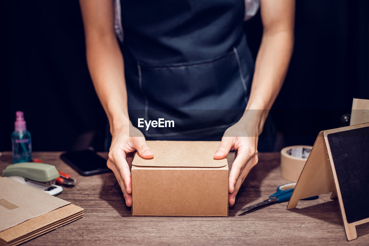 Midsection of woman doing packaging in office