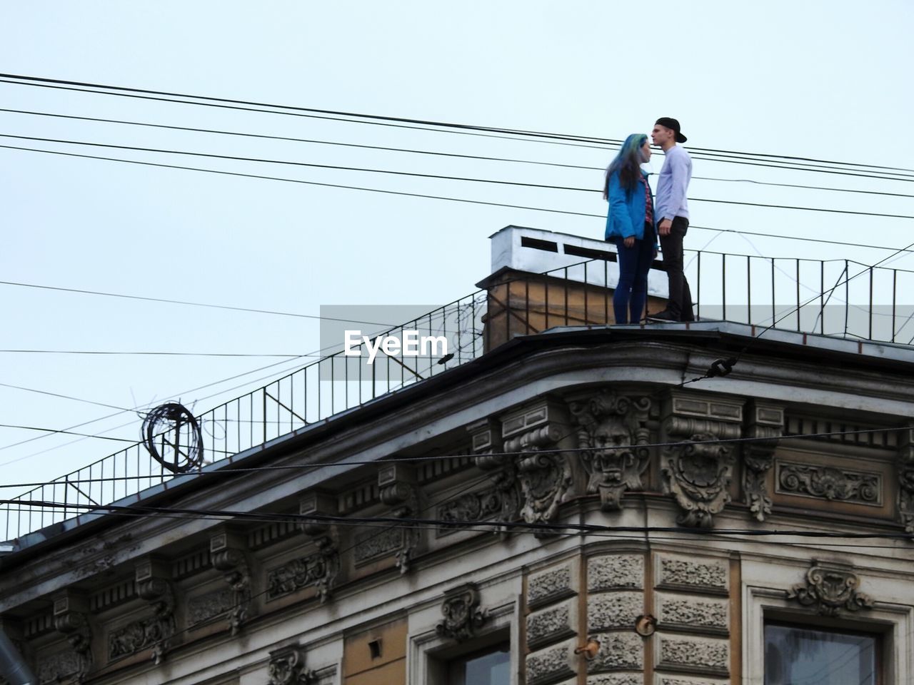 LOW ANGLE VIEW OF MAN STANDING BY RAILING