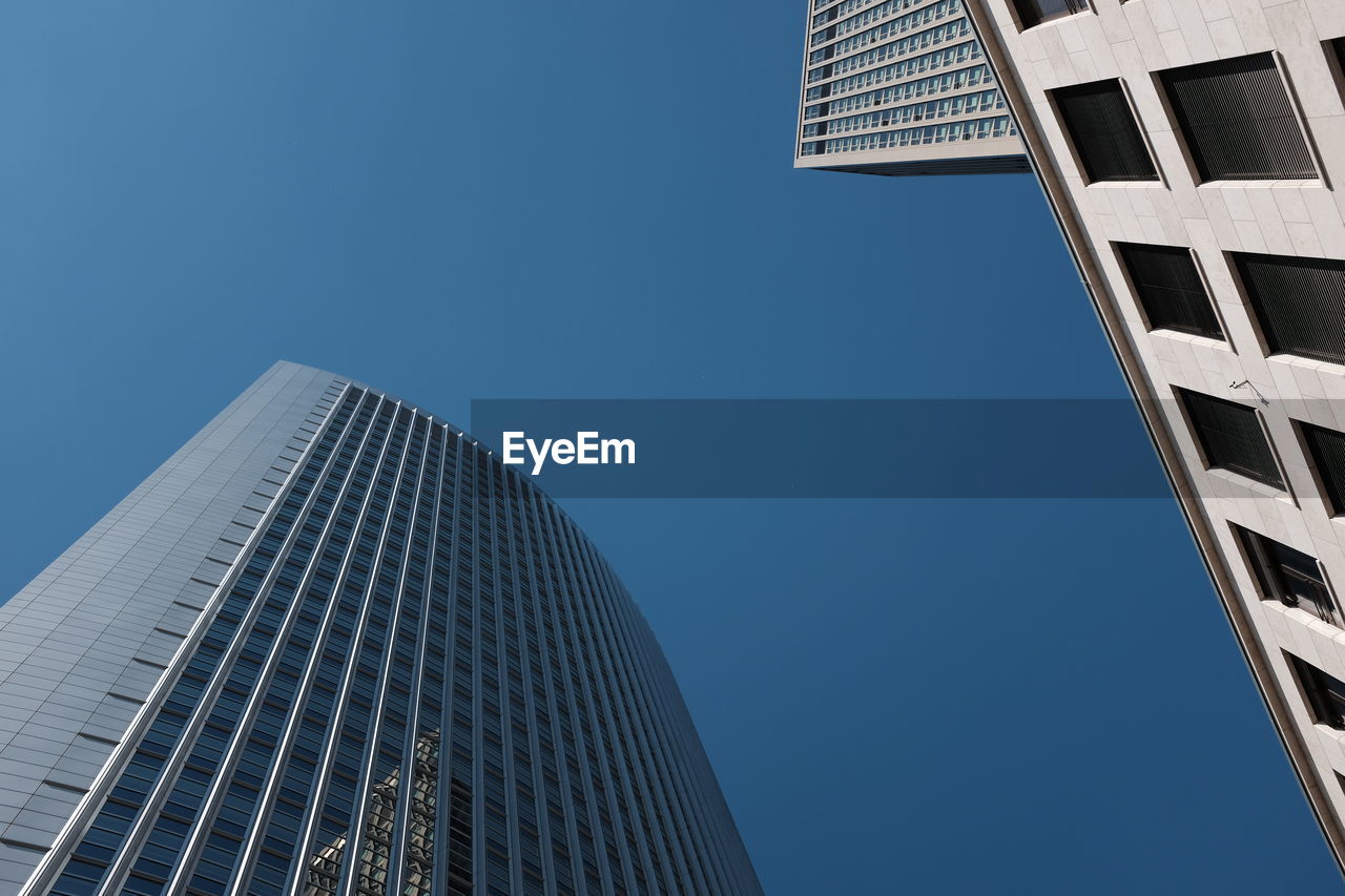 Low angle view of modern buildings against clear blue sky