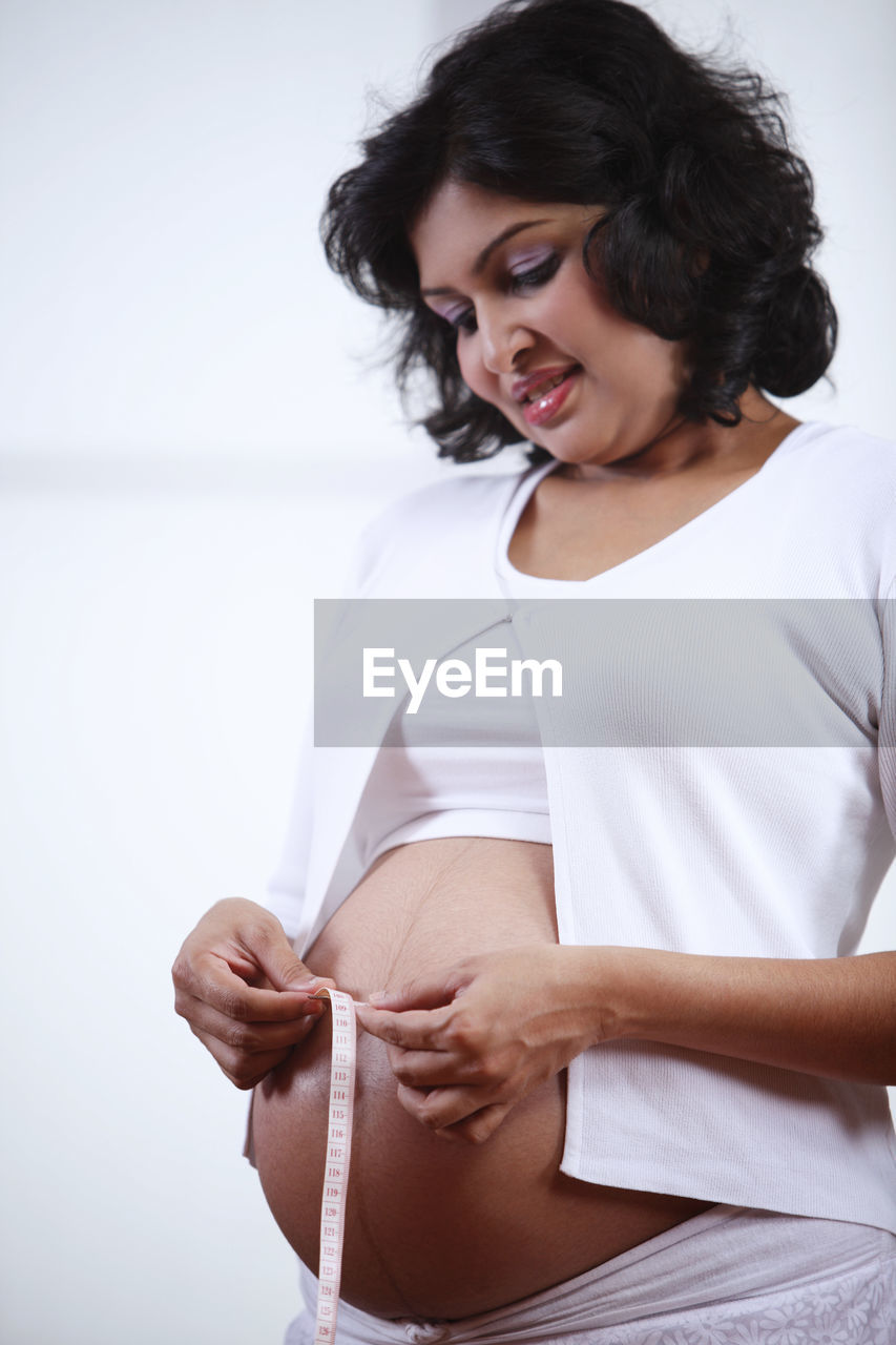 Pregnant woman measuring belly at home