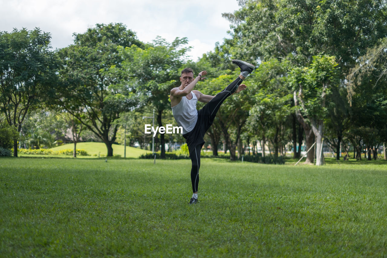 Full length of young man exercising on field