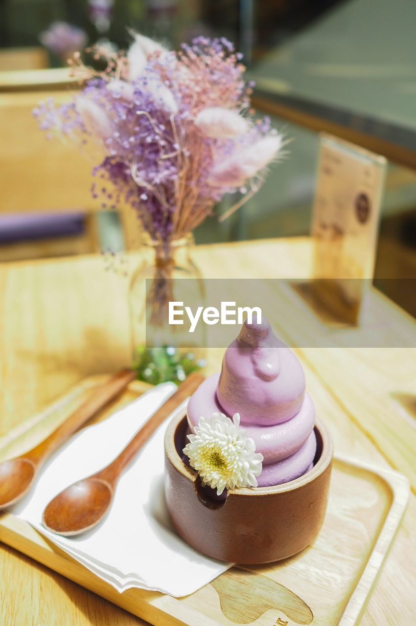 CLOSE-UP OF ICE CREAM CONE ON WOODEN TABLE