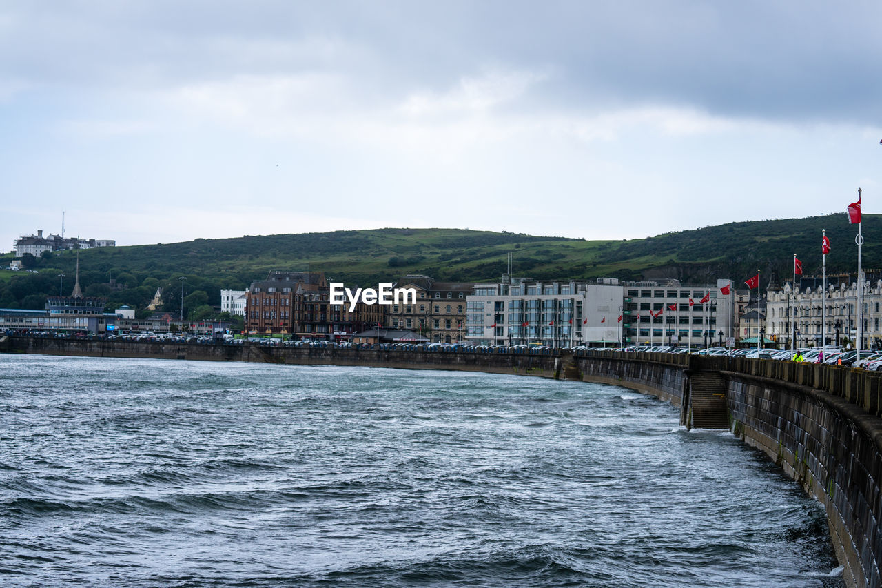 BRIDGE OVER SEA BY BUILDINGS AGAINST SKY